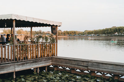 Stilt house over lake against sky