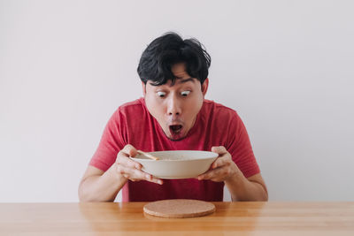 Portrait of mature man holding bowl on table