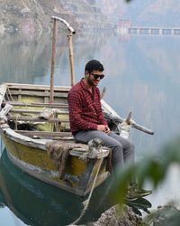 Young man sitting on fishing boat in lake