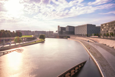 Scenic view of canal in city against cloudy sky