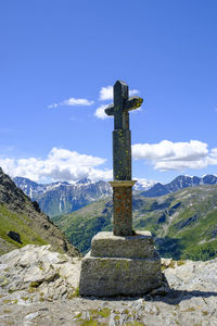 Cross on rock against sky