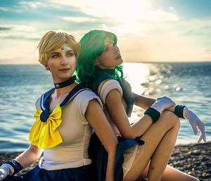 Portrait of smiling friends sitting at beach