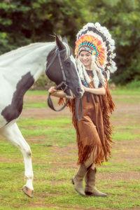 Full length portrait of young woman standing on field