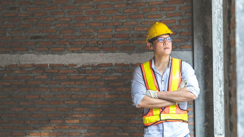 Low angle view of man working at construction site against brick wall