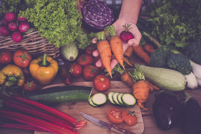 Cropped hand holding vegetables in kitchen