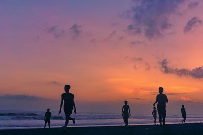 Silhouette people on beach against sky during sunset