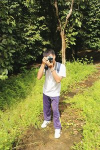 Full length of man photographing while standing in forest