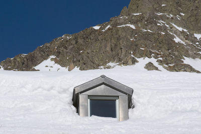 Low angle view of house on snow covered mountain against sky