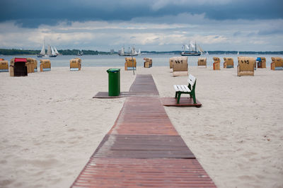 Hooded chairs on beach against sky