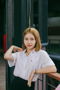 Portrait of smiling woman standing against wall