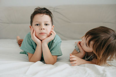 Older brother and younger sister playing in the bedroom on the bed. high quality photo