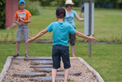 Boys playing hopscotch while mother standing at playground