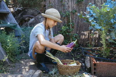 Midsection of woman holding basket while standing by plants