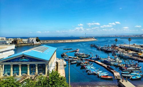 High angle view of sailboats moored in sea against blue sky