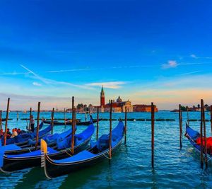 Gondolas moored in river against st marks square at sunset