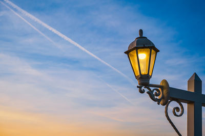 Electric lamp in retro style on a wooden pole. the lamp glows against the background of the sky 