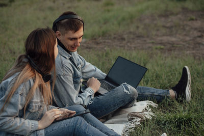 Man and a woman with a laptop and tablet while working using laptop, sitting in park