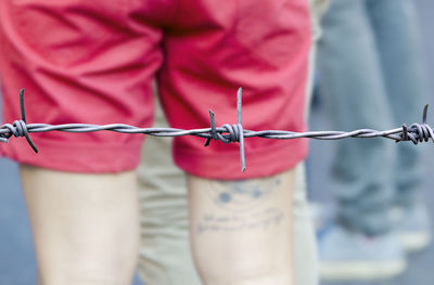 Close-up of man's midsection behind barbed wire