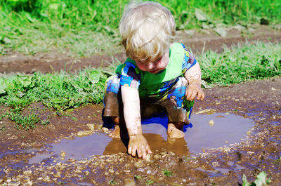 Boy playing in muddy puddle