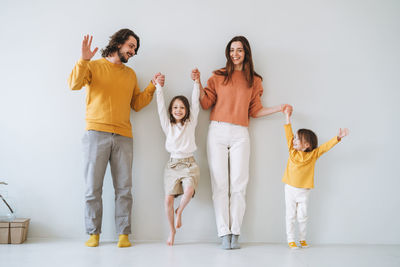 Young happy family with two children girls on the background of gray wall