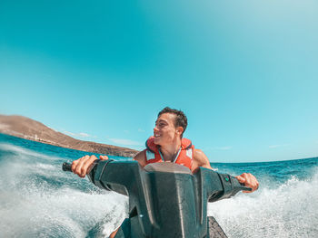 Man photographing sea against clear sky