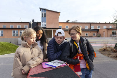 Teenage friends standing in front of school