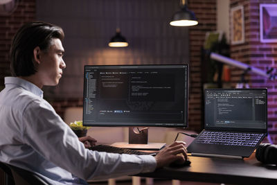 Side view of young woman using laptop at office