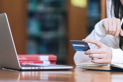 Midsection of woman using laptop on table