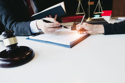 Midsection of man reading book on table