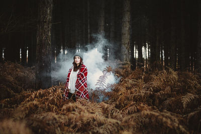 Young woman standing on field in forest