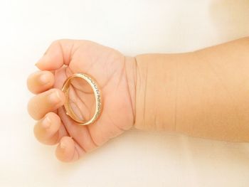 Close-up of woman hand holding ring over white background