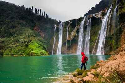 Rear view of man standing by waterfall