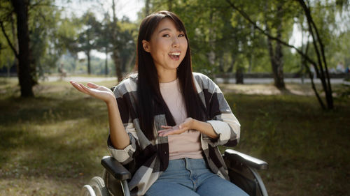 Young woman using mobile phone while sitting on field