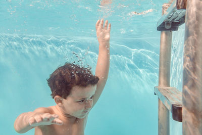 Midsection of shirtless man swimming in pool