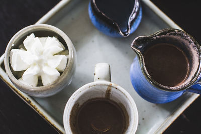 High angle view of hot chocolate in pitcher with cream on tray