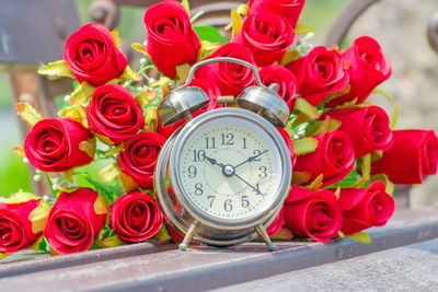 Alarm clock with artificial roses on table