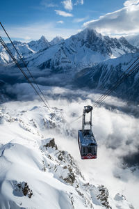 Ski lift over snowcapped mountains against sky