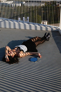 Full length of young woman lying down on elevated walkway