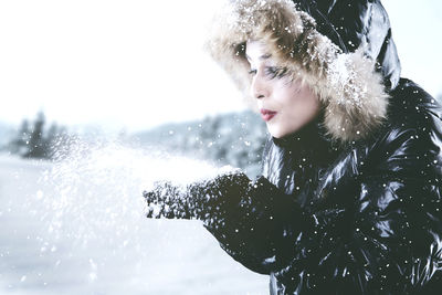 Woman blowing snow during winter