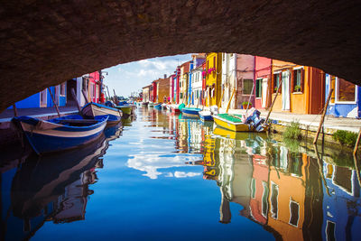 Boats moored in canal amidst buildings