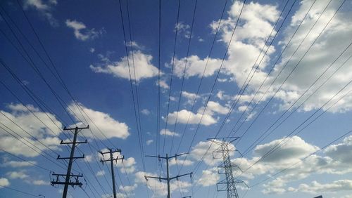 Low angle view of electricity pylon against cloudy sky