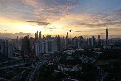 Aerial view of modern buildings in city against sky during sunset