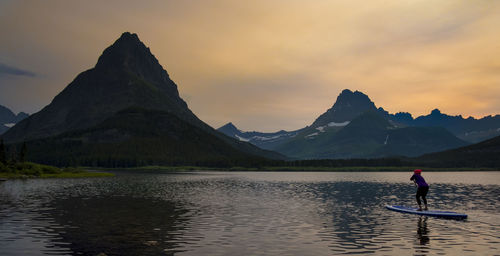 Person on lake against sky during sunset