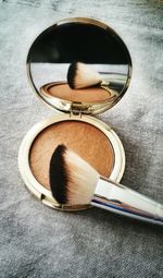 High angle view of powder compact with make-up brush