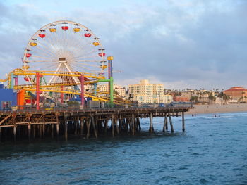 Ferris wheel by sea against sky