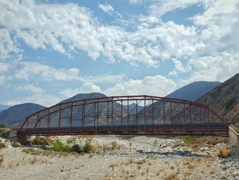 Old greenspot bridge by mountains against sky