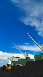 Low angle view of cranes against blue sky