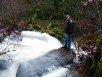 Man standing in river amidst trees