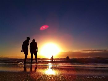 Silhouette of people on beach at sunset