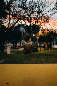 Rear view of boy swinging at park